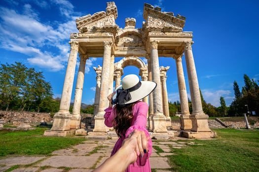 Women tourists holding man's hand and leading him to Aphrodisias ancient city in Turkey.