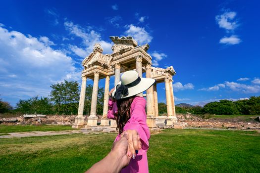 Women tourists holding man's hand and leading him to Aphrodisias ancient city in Turkey.
