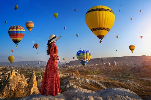 Beautiful girl standing and looking to hot air balloons in Cappadocia, Turkey.