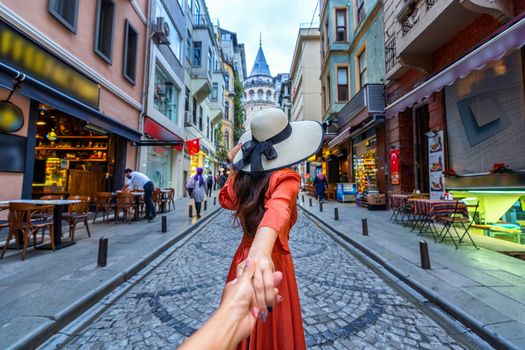 Women tourists holding man's hand and leading him to Galata tower in Istanbul, Turkey.