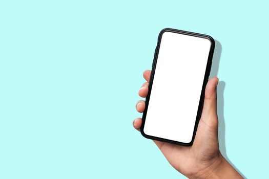 Hand holding smartphone on pastel blue background.