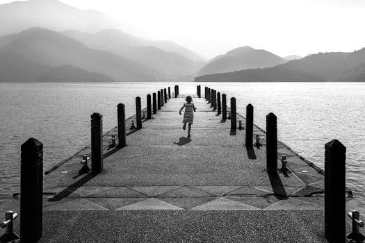 Black and white of Little girl running on pathway in Sun moon lake, Taiwan.