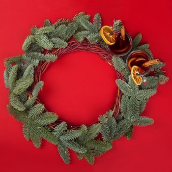 Christmas decorative wreath with noble fir tree twigs and mulled wine on red paper background with copy space for text