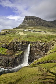 Gasadalur waterfall from viewpoint during a sunny autumn day with the water coming up under a strong wind (Faroe Islands, Denmark, Europe)