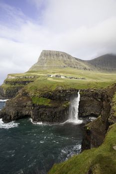 Gasadalur waterfall from viewpoint during a sunny autumn day with the water coming up under a strong wind (Faroe Islands, Denmark, Europe)