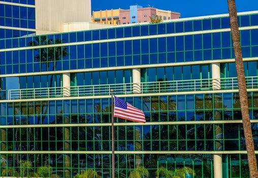 American Flag by Blue Glass Building in Tropical Setting