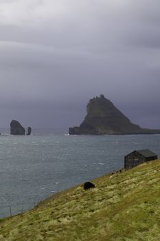 Tindholmur and Drangarnir with dramatic stormy sky as background, Faroe Islands