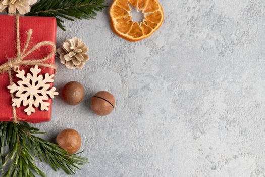 Christmas or New Year gray background with decorations from natural materials - Christmas tree twigs, nuts, cones, wooden snowflake and dried orange.