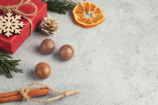 Christmas or New Year gray background with decorations from natural materials - Christmas tree twigs, nuts, cones, wooden snowflake and dried orange.