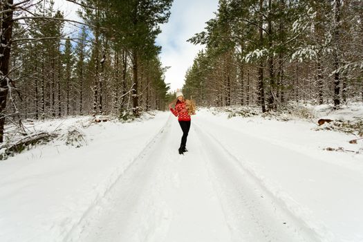 Festive joyful woman holds a rustic Christmas tree and stuffed toy outside in the snow