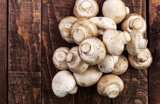 Heap of fresh champignon mushrooms on wooden table, top view. Copy space