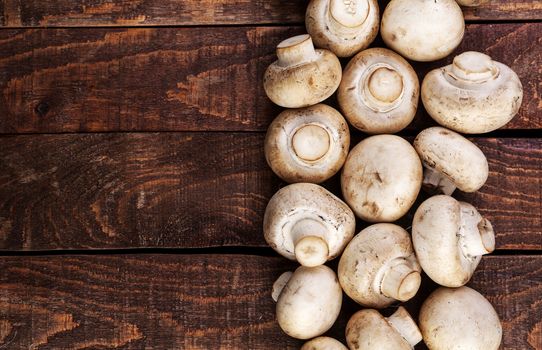 Heap of fresh champignon mushrooms on wooden table, top view. Copy space