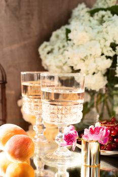 Rose wine in glasses. Rose wine on golden bottles background with flowers and fruits