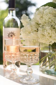 Rose blush wine in glasses. Bottle of rose wine with flowers on background. Prosecco.