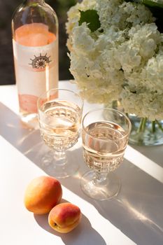 Rose wine in glasses. Rose wine on golden bottles background with flowers and fruits