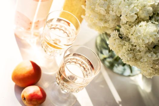 Rose wine in glasses. Rose wine on golden bottles background with flowers and fruits