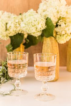 Rose wine in glasses. Rose wine on golden bottles background with flowers