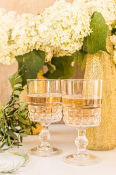 Rose wine in glasses. Rose wine on golden bottles background with flowers