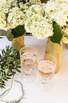 Rose wine in glasses. Rose wine on golden bottles background with flowers