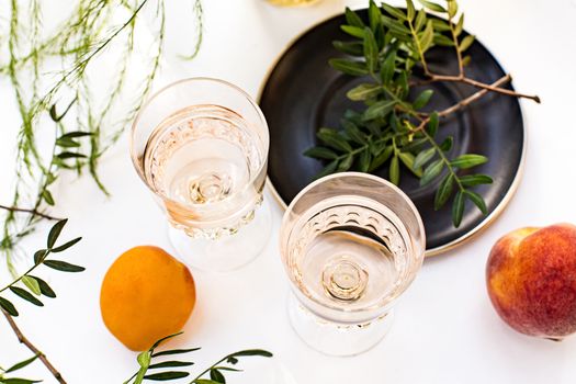 Rose wine in glasses. Rose wine on golden bottles background with flowers and fruits