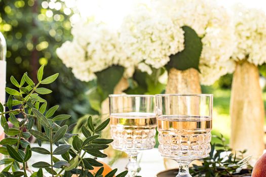 Rose wine in glasses. Rose wine on golden bottles background with flowers and fruits