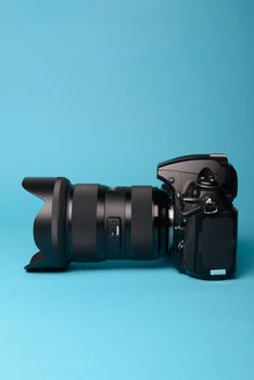 Professional modern DSLR camera against blue background