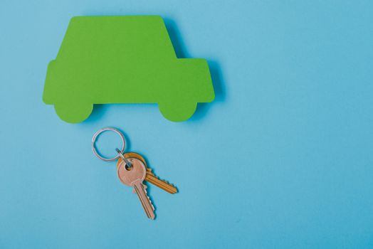 paper green cars figure with keys. top view on blue background