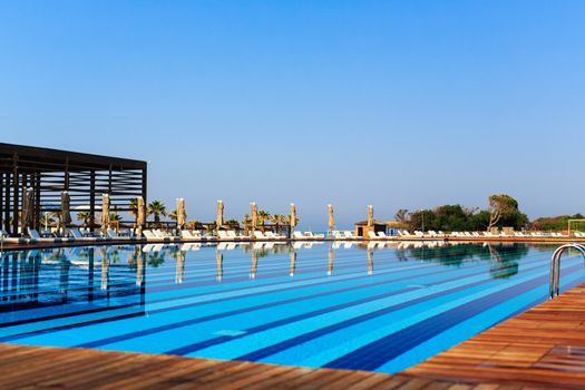 pool with wooden banks in the morning with palm trees on the beach umbrellas stacked sun beds empty without people