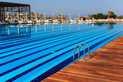 pool with wooden banks in the morning with palm trees on the beach umbrellas stacked sun beds empty without people