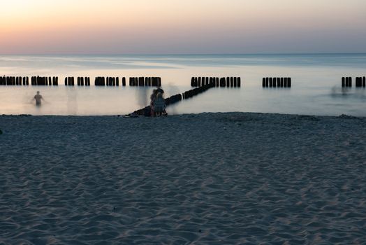 A photograph of wooden breakwater and seagulls at sunset on the Baltic Sea