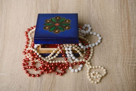 A photograph of gift box and red beads necklace on wooden background