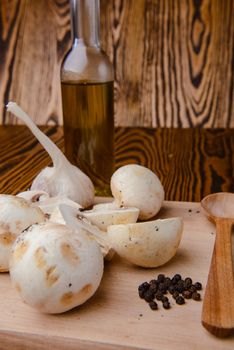 composition poured olive oil, mushrooms, garlic on wooden background. healthy food