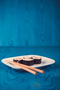 Appetizing tasty Japan rolls on a plate isolated on blue wooden background