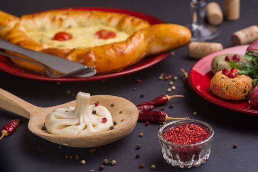 Georgian food on black table. khinkali, phali,  khachapuri with tomatos and adjika