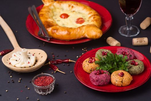 Georgian food on black table. khinkali, phali,  khachapuri with tomatos, adjika and a glass of wine.