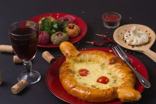 Georgian food on black table. khinkali, phali,  khachapuri with tomatos, adjika and a glass of wine.