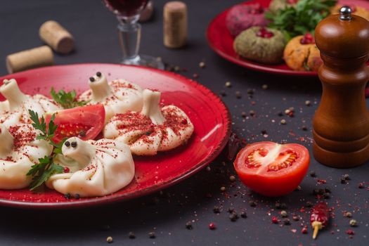 Georgian food on black table. khinkali, phali,  khachapuri with tomatos, adjika and a glass of wine.