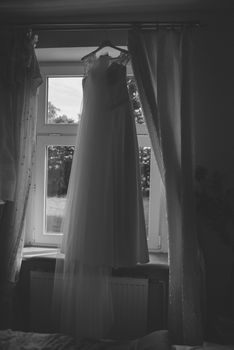 Bridesmaid helping slender bride lacing her wedding white dress, buttoning on delicate lace pattern with fluffy skirt on waist. Morning bridal preparation details newlyweds. Wedding day moments, wear.