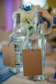 Bottle of cold vodka and wine bottle in bucket with ice and orange juice in jug on table, copy space. Alcohol bottles in ice bucket in restaurant. Wedding party