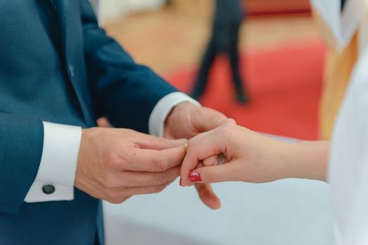 the bride and groom during the wedding ceremony put wedding rings on their fingers.