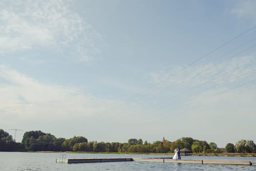 Bride and groom at a photo session in the nature. Lake and pier.