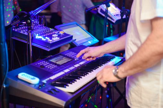 DJ plays music at wedding party. Colorful light rays.