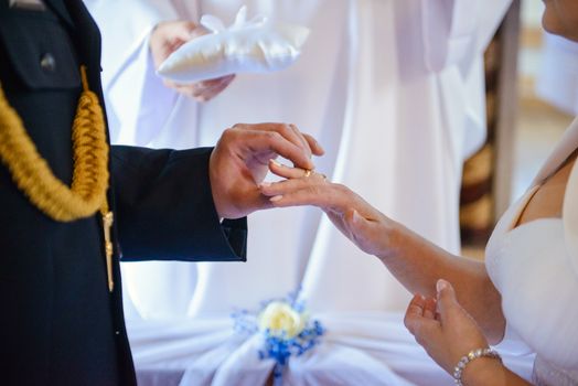 the bride and groom during the wedding ceremony put wedding rings on their fingers.