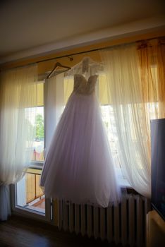 Bridesmaid helping slender bride lacing her wedding white dress, buttoning on delicate lace pattern with fluffy skirt on waist. Morning bridal preparation details newlyweds. Wedding day moments, wear.