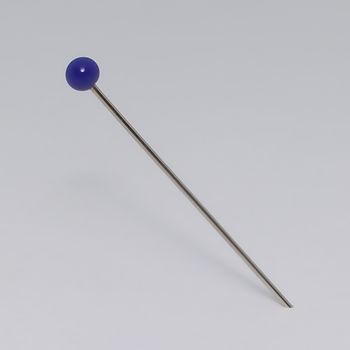 A close up of a single blue pin in a sheet of paper