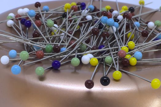 A stack of pins on a copper pincushion