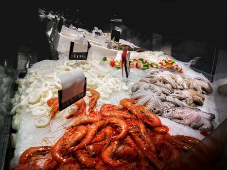 fishmonger bar counter with shrimps , octopus and other fresh seafood .