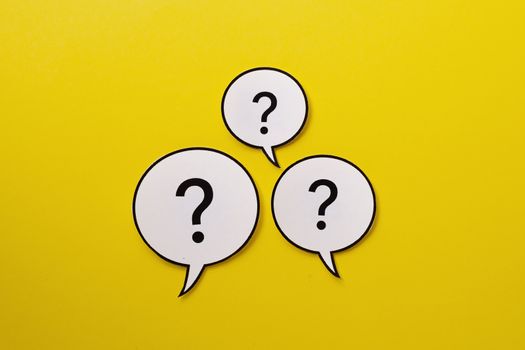 Three speech bubbles with question marks centered over a bright yellow background with copy space
