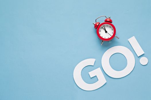 Countdown to the start of a contest or specific period of time with a red alarm clock alongside the word Go over blue with copy space