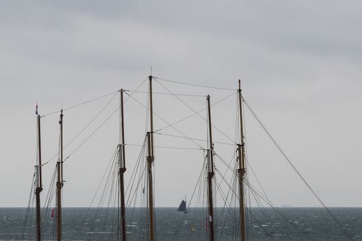 Sailboat in the Wadden Sea as seen through the masts of two three-masted sailboats
